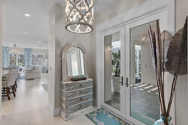 entryway with french doors, recessed lighting, wood finished floors, and a notable chandelier