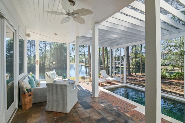 sunroom featuring a water view and a ceiling fan