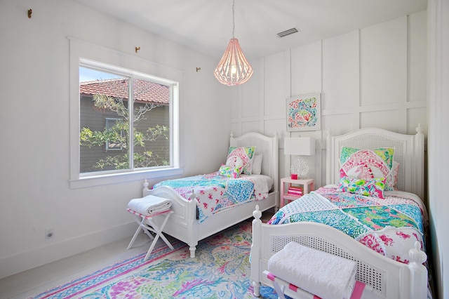 bedroom featuring multiple windows, visible vents, and a decorative wall