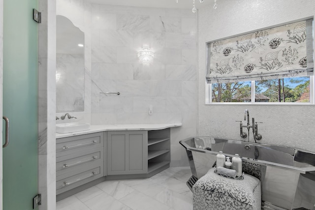 bathroom with marble finish floor, a freestanding bath, tile walls, and vanity