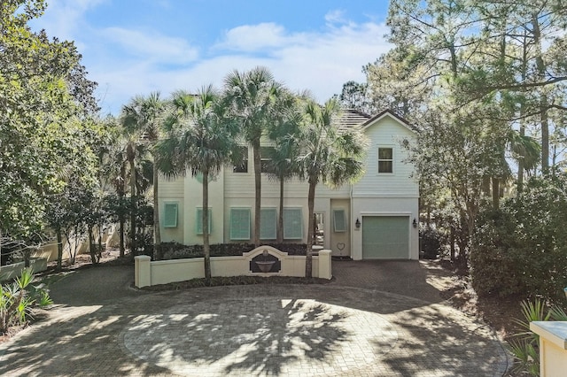 view of front of property featuring decorative driveway, an attached garage, and stucco siding