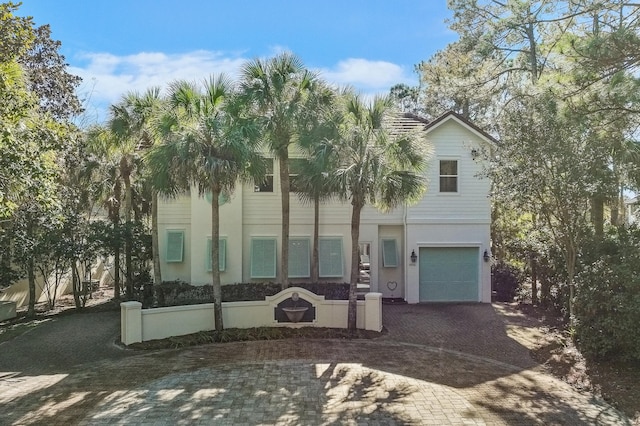 view of property with decorative driveway, an attached garage, and stucco siding