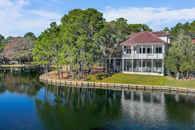 rear view of property with a yard, a water view, and a balcony