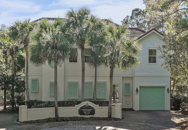 view of front facade featuring decorative driveway, an attached garage, and stucco siding