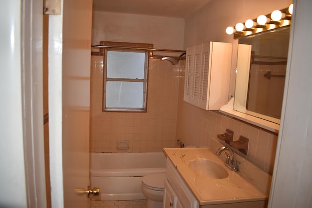 full bathroom featuring tiled shower / bath, tile walls, tile patterned flooring, vanity, and toilet