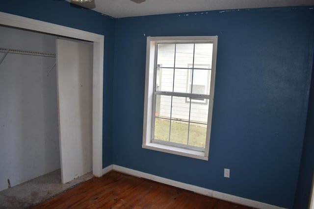 unfurnished bedroom with dark hardwood / wood-style flooring and a closet