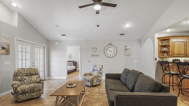 tiled living room featuring ceiling fan, french doors, vaulted ceiling, and a textured ceiling