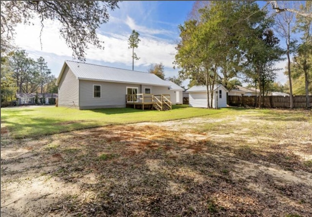 rear view of house with a shed, a wooden deck, and a lawn