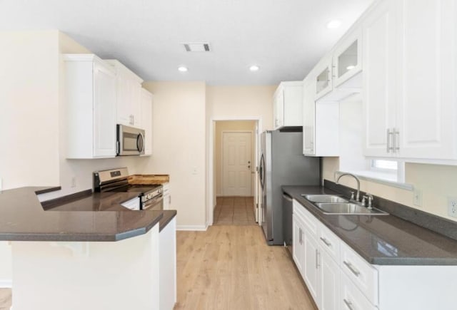 kitchen with stainless steel appliances, kitchen peninsula, sink, and white cabinets