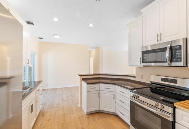 kitchen featuring stainless steel appliances, kitchen peninsula, white cabinets, and light hardwood / wood-style flooring