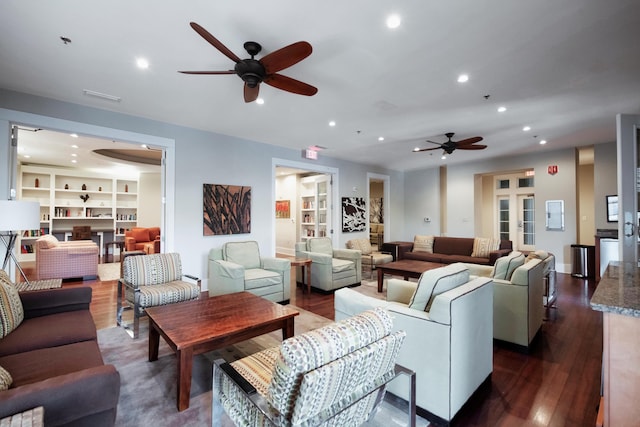 living room featuring built in features, dark hardwood / wood-style floors, and ceiling fan