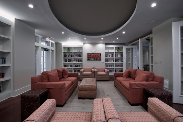 living room with built in shelves and a tray ceiling