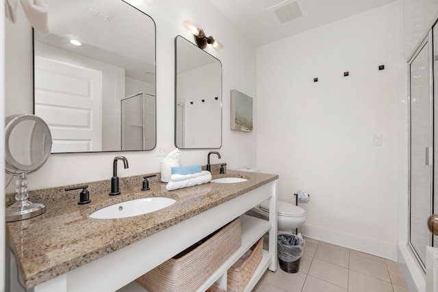 bathroom featuring toilet, vanity, a shower with door, and tile patterned flooring