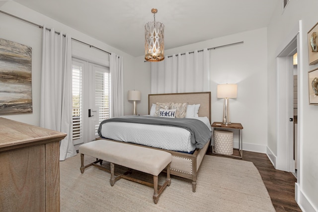 bedroom with wood-type flooring, access to exterior, and a chandelier