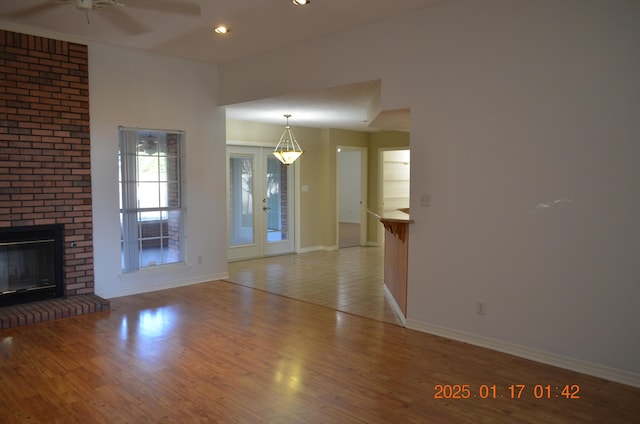 unfurnished living room with ceiling fan, a fireplace, and light hardwood / wood-style flooring