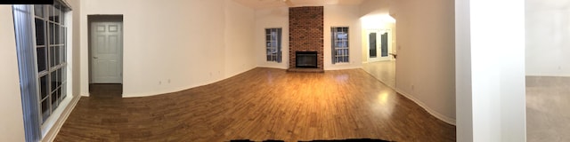 unfurnished living room with a brick fireplace and dark hardwood / wood-style floors