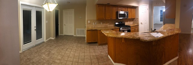 kitchen with pendant lighting, backsplash, stainless steel appliances, and kitchen peninsula