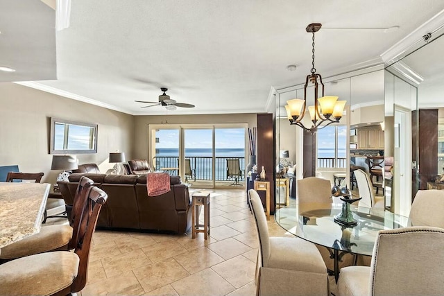 dining area with a water view, light tile patterned floors, crown molding, and ceiling fan with notable chandelier