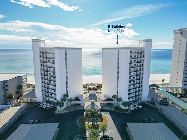 view of building exterior featuring a water view and a beach view