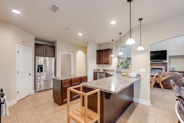 kitchen with stainless steel appliances, a kitchen breakfast bar, hanging light fixtures, kitchen peninsula, and light tile patterned flooring