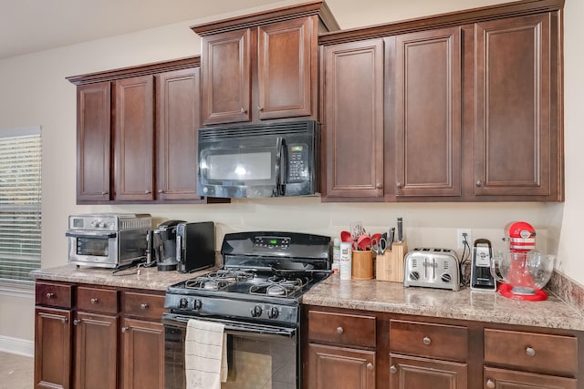 kitchen featuring light stone counters and black appliances