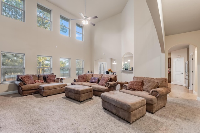 living room with ceiling fan, a high ceiling, and light carpet