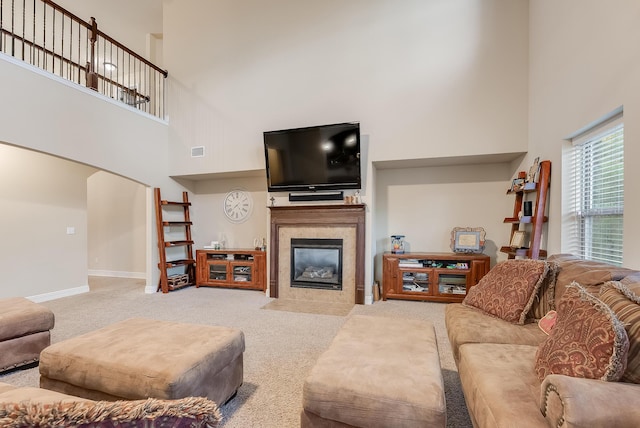 living room with light carpet, a towering ceiling, and a tiled fireplace