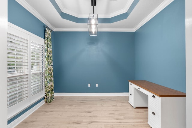 unfurnished office with light wood-type flooring, crown molding, and a raised ceiling