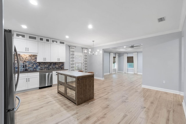 kitchen featuring tasteful backsplash, white cabinets, hanging light fixtures, and stainless steel appliances