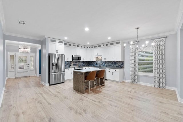 kitchen featuring an inviting chandelier, appliances with stainless steel finishes, pendant lighting, a breakfast bar, and a center island