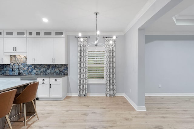 kitchen with sink, hanging light fixtures, white cabinets, and tasteful backsplash