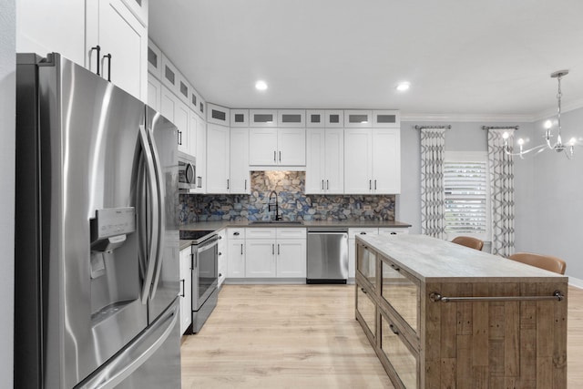 kitchen featuring tasteful backsplash, pendant lighting, sink, appliances with stainless steel finishes, and white cabinets