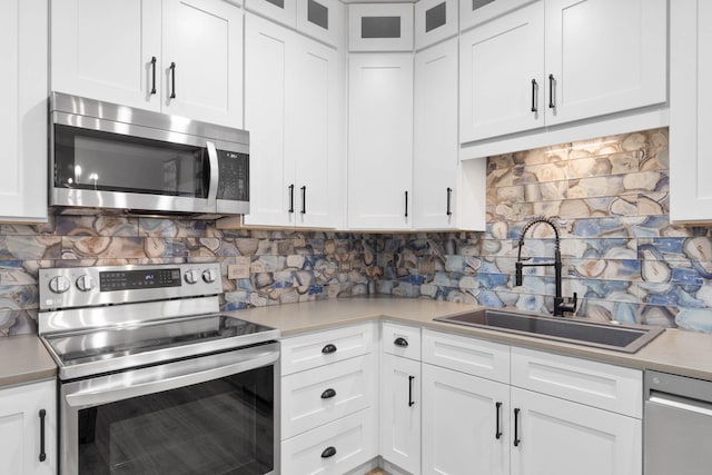 kitchen with appliances with stainless steel finishes, backsplash, white cabinetry, and sink