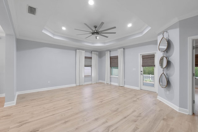 unfurnished living room featuring light wood-type flooring, ceiling fan, ornamental molding, and a tray ceiling