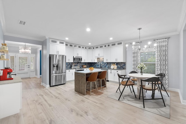 kitchen featuring stainless steel appliances, white cabinetry, hanging light fixtures, and a notable chandelier