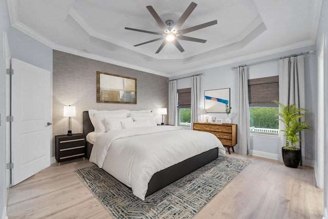 bedroom featuring ceiling fan, light hardwood / wood-style floors, crown molding, and a raised ceiling