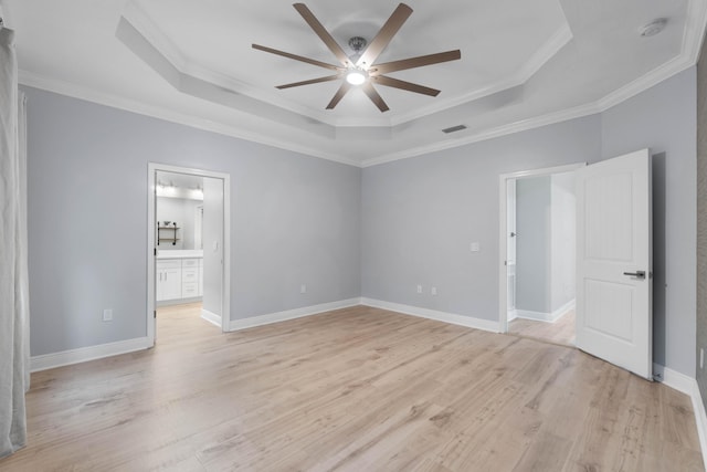 unfurnished bedroom featuring ornamental molding, a raised ceiling, ceiling fan, ensuite bathroom, and light hardwood / wood-style flooring