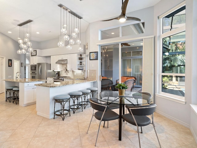 kitchen featuring white cabinetry, stainless steel appliances, a kitchen breakfast bar, and decorative light fixtures