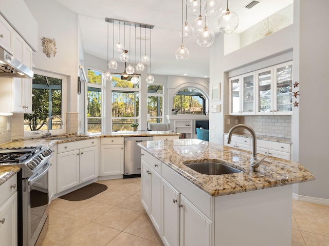 kitchen featuring decorative backsplash, appliances with stainless steel finishes, sink, and a center island with sink