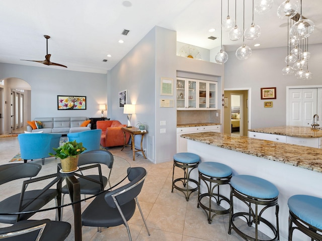 kitchen with white cabinetry, tasteful backsplash, light tile patterned floors, pendant lighting, and a towering ceiling