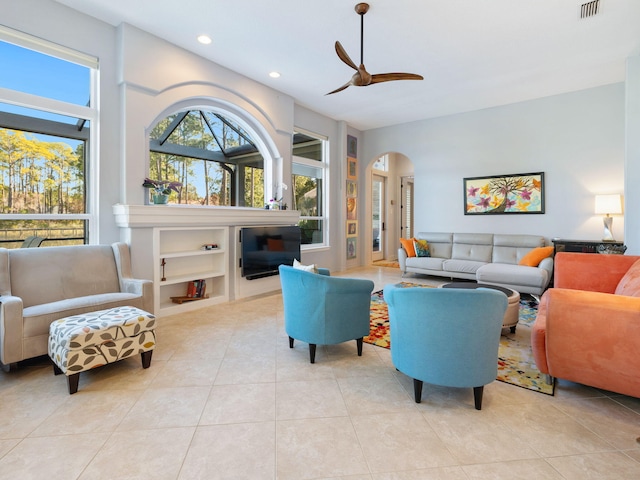 tiled living room featuring built in shelves and ceiling fan