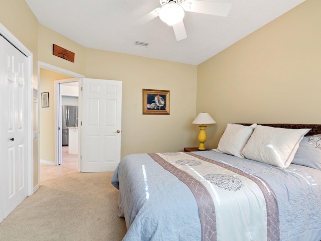 bedroom with ceiling fan, light colored carpet, and a closet