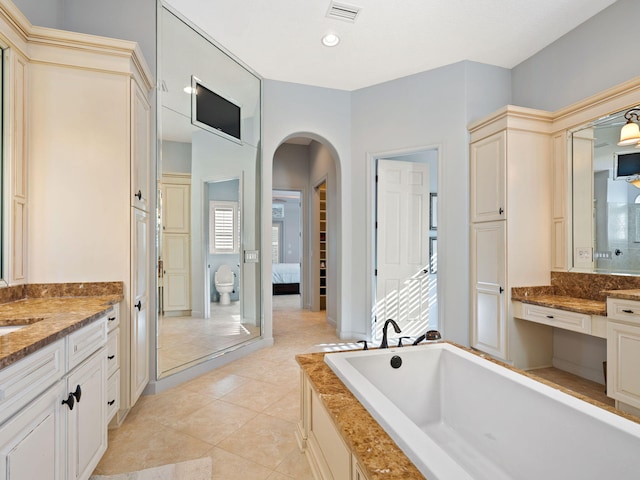 bathroom with tile patterned flooring, vanity, and a relaxing tiled tub