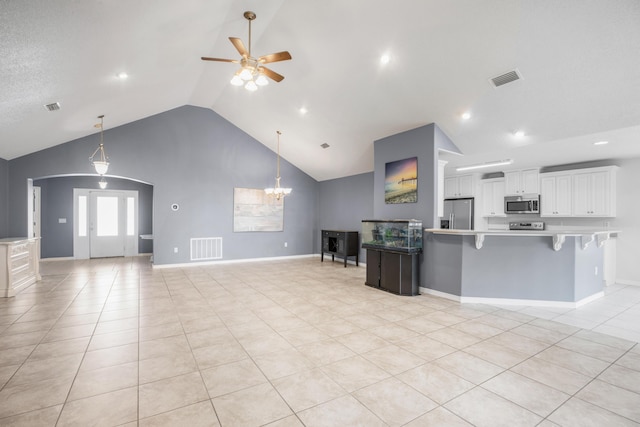 interior space featuring white cabinetry, light tile patterned floors, appliances with stainless steel finishes, a kitchen breakfast bar, and ceiling fan with notable chandelier