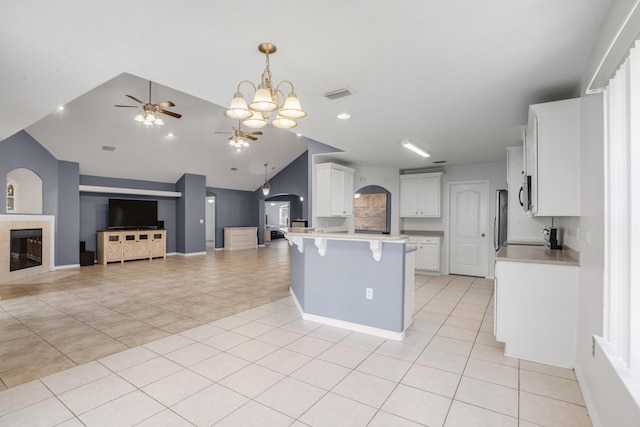 kitchen featuring white cabinetry, stainless steel appliances, a center island, a tile fireplace, and a kitchen breakfast bar