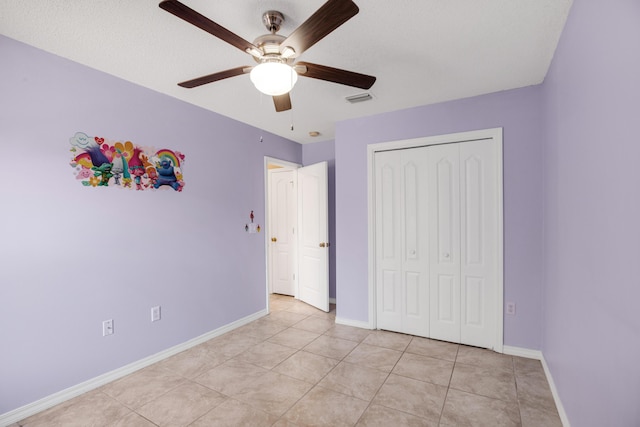 unfurnished bedroom with ceiling fan, light tile patterned flooring, and a closet