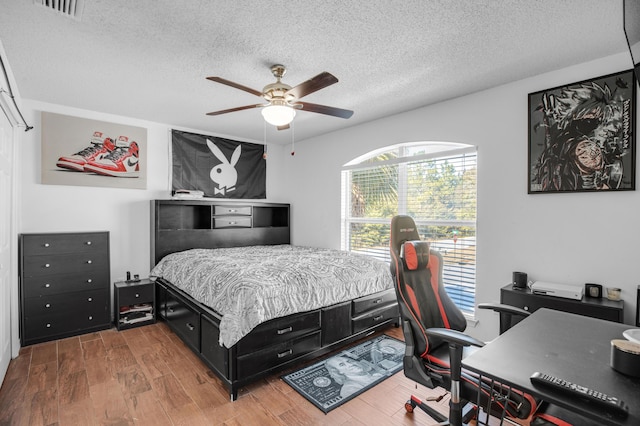 bedroom with hardwood / wood-style flooring, ceiling fan, and a textured ceiling