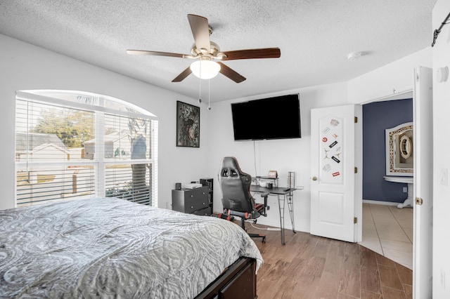 bedroom with a textured ceiling, hardwood / wood-style flooring, and ceiling fan