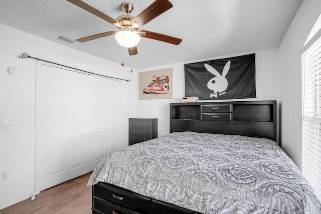 bedroom featuring ceiling fan, a closet, wood-type flooring, and a textured ceiling