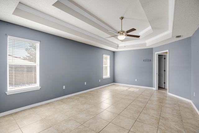 tiled empty room with a tray ceiling, a textured ceiling, and ceiling fan